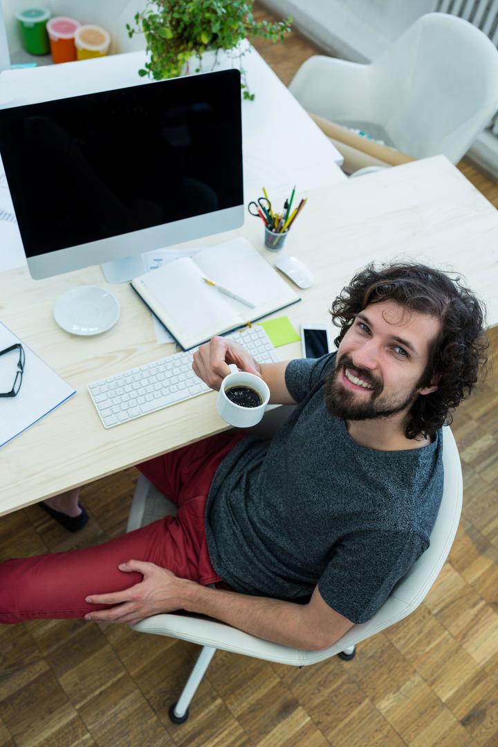 Male Graphic Designer Enjoying Coffee at Desk - Free Images, Stock Photos and Pictures on Pikwizard.com