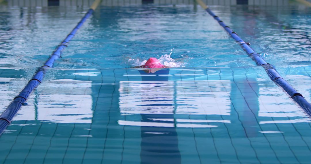 Swimmer in Pink Cap Doing Freestyle in Indoor Pool - Free Images, Stock Photos and Pictures on Pikwizard.com