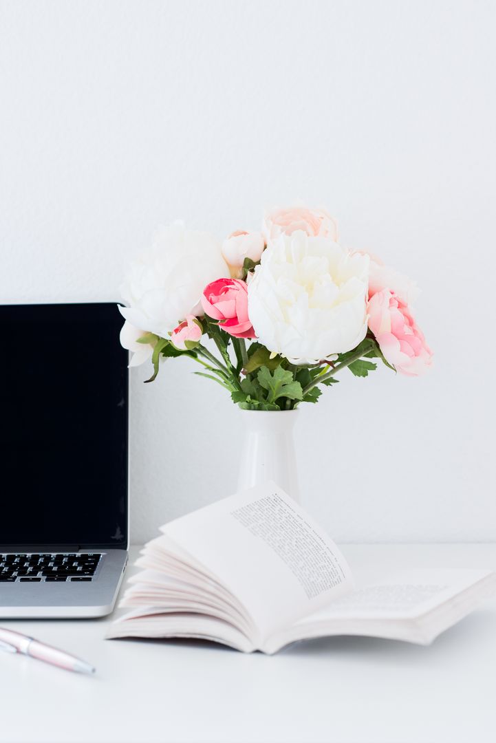 Technology laptop and flowers on desk with open book for creative workspace inspiration