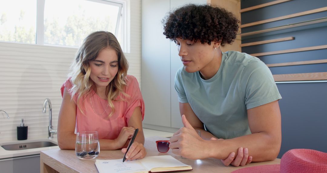 Couple Collaborating and Smiling While Writing in Kitchen