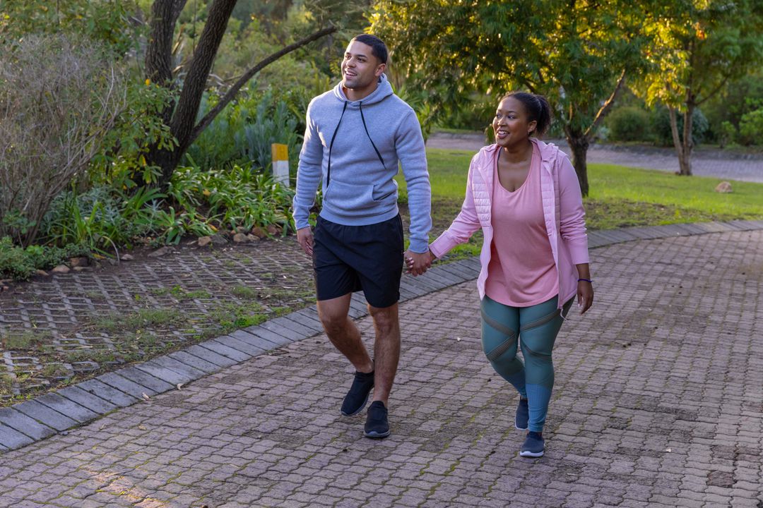 Couple Strolling Hand in Hand Through Sunny Park Pathway