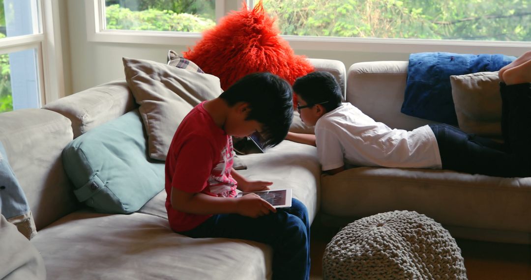 Children Relaxing on Sofa Playing with Tablets - Free Images, Stock Photos and Pictures on Pikwizard.com