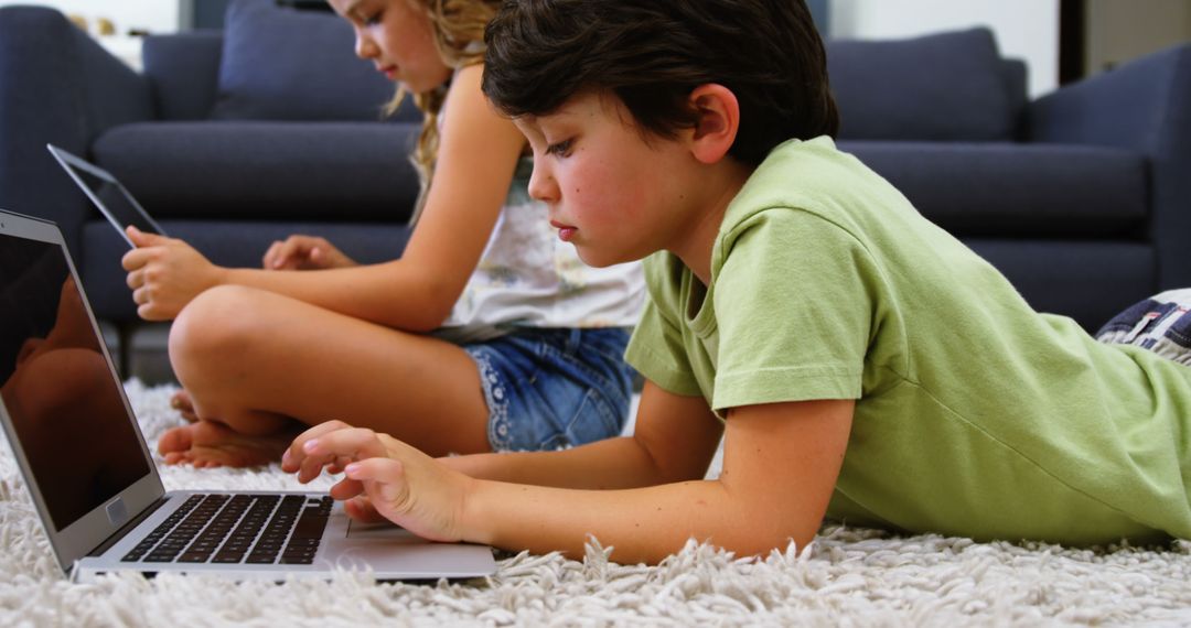 Focused Children Using Laptops and Tablets on Carpet - Free Images, Stock Photos and Pictures on Pikwizard.com