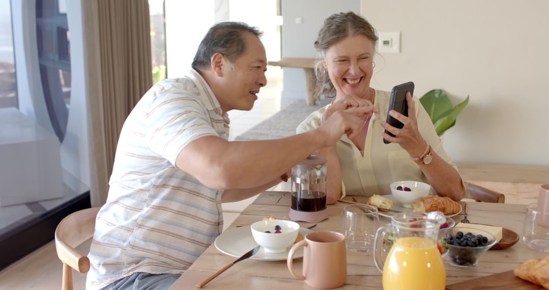 Senior Couple Enjoying Breakfast Together Using Smartphone