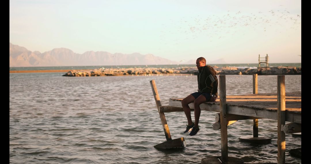 Young Runner Relaxing on Pier Overlooking Serene Beachscape