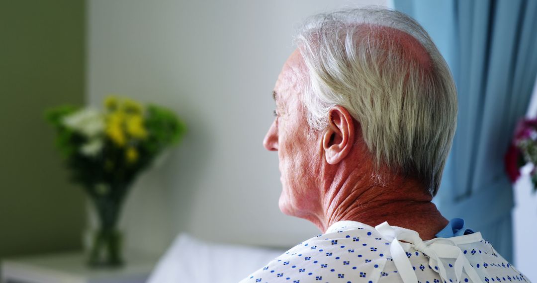 Senior Man in Hospital Gown Facing Away with Flowers in Background - Free Images, Stock Photos and Pictures on Pikwizard.com