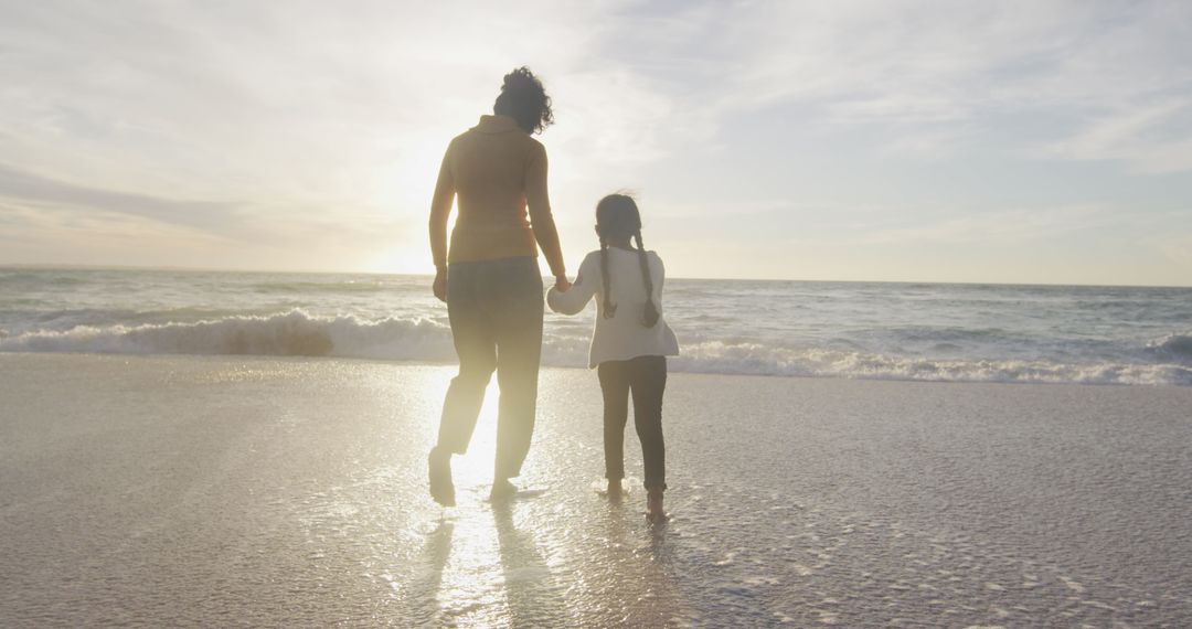 Mother and Daughter Walking on Beach at Sunset