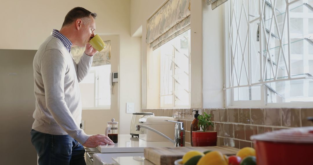 Man Drinking Coffee in Bright Kitchen with Sunlight Through Windows - Free Images, Stock Photos and Pictures on Pikwizard.com