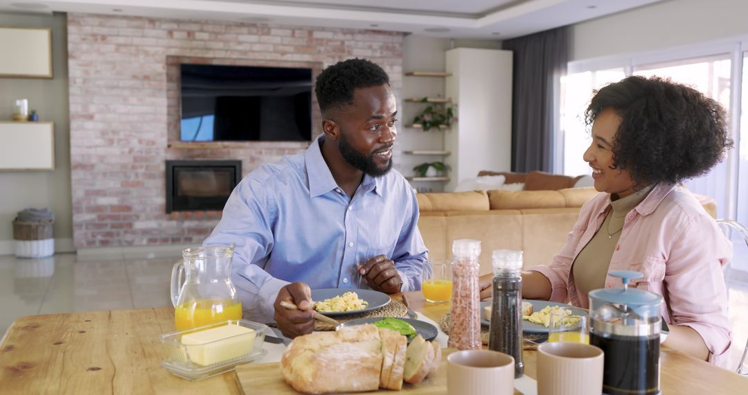 Diverse couple enjoying morning breakfast with coffee and bread in modern open-plan home