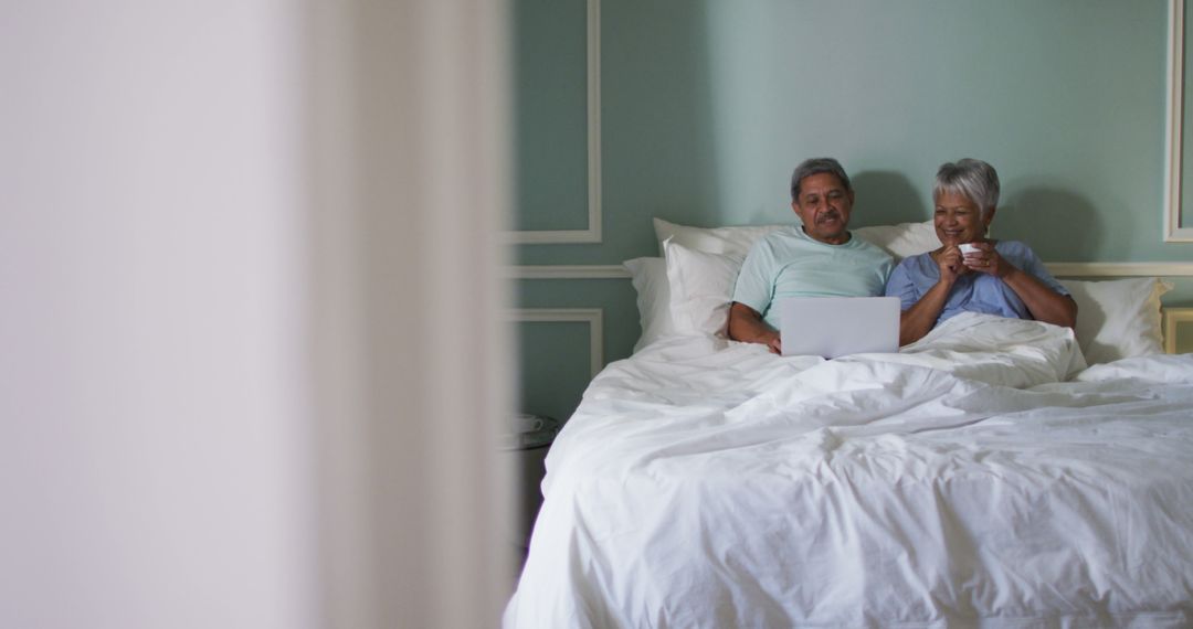 Senior Couple Enjoying Relaxing Time in Bed with Laptop