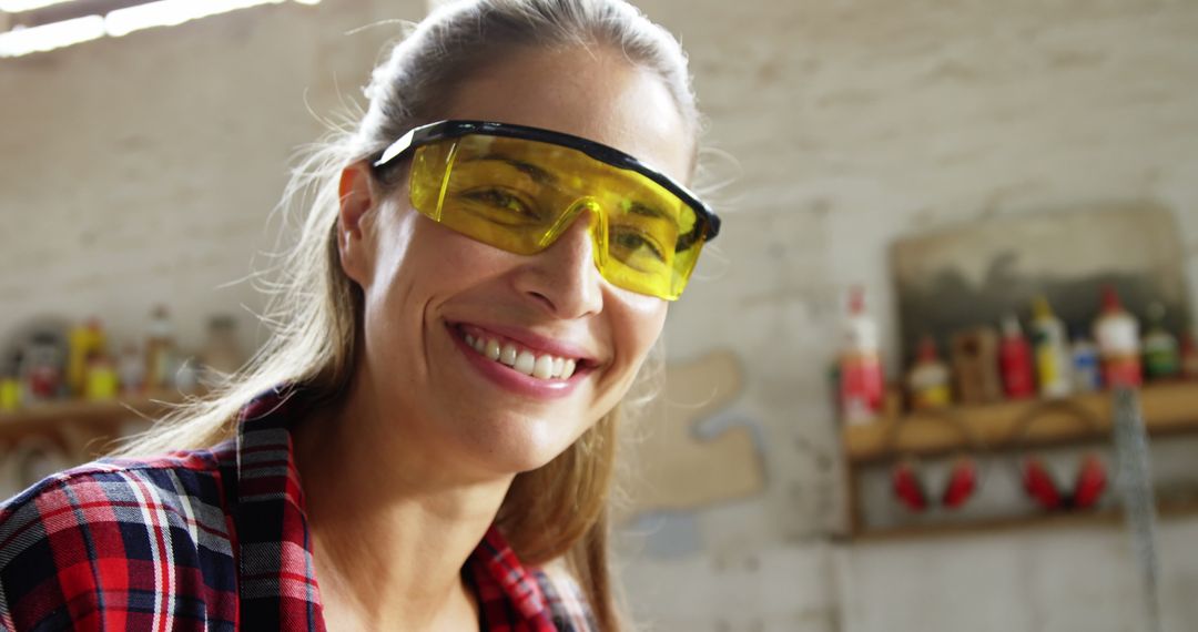 Smiling Female Carpenter Wearing Safety Glasses in Workshop - Free Images, Stock Photos and Pictures on Pikwizard.com