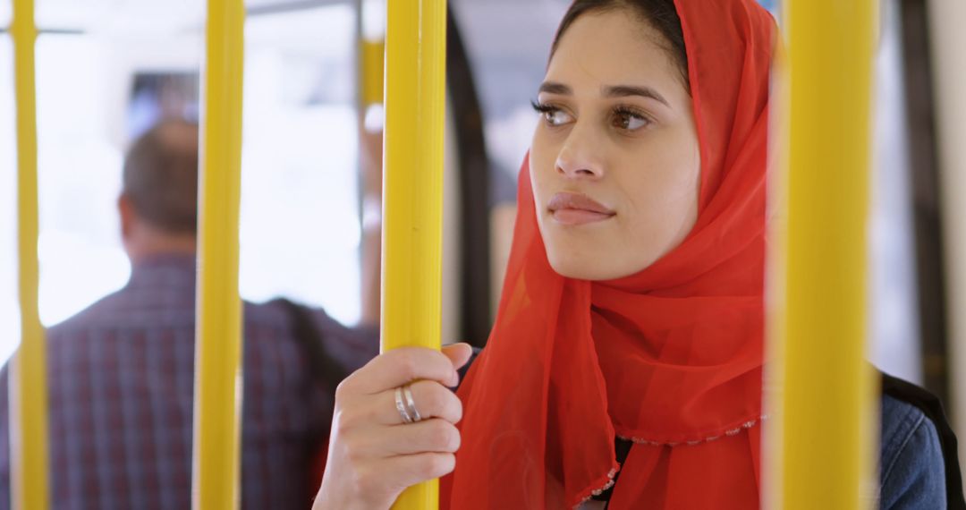 Woman in Red Hijab Traveling by Public Transport Looking Thoughtful - Free Images, Stock Photos and Pictures on Pikwizard.com