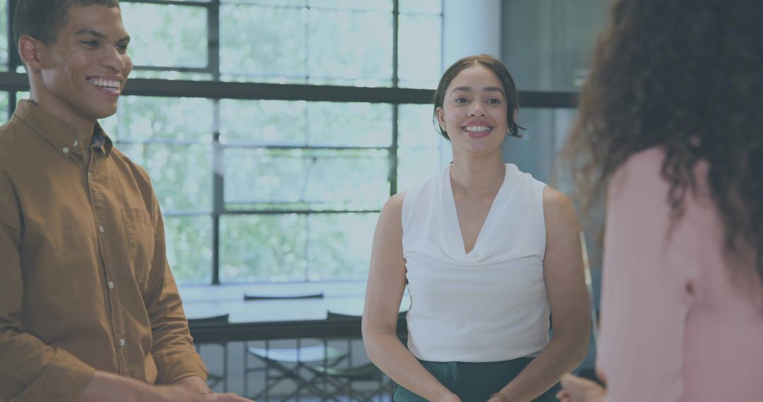Smiling young professionals chatting and collaborating in bright modern office meeting space