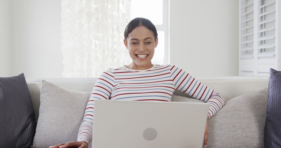 Smiling Latina Woman Using Laptop on Modern Sofa - Free Images, Stock Photos and Pictures on Pikwizard.com