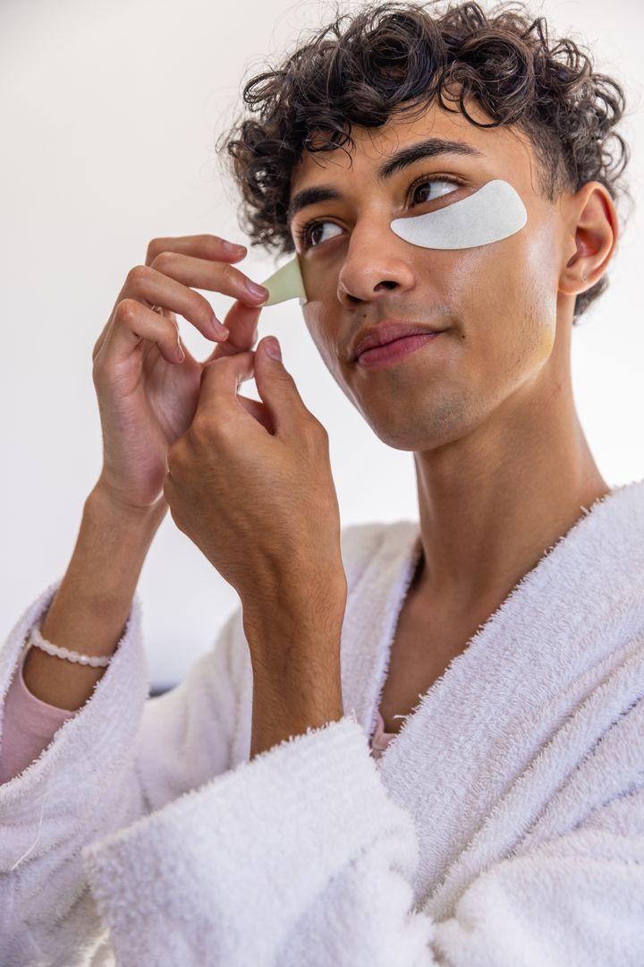 Young Man Applying Eye Patches for Skincare Routine in Bathroom
