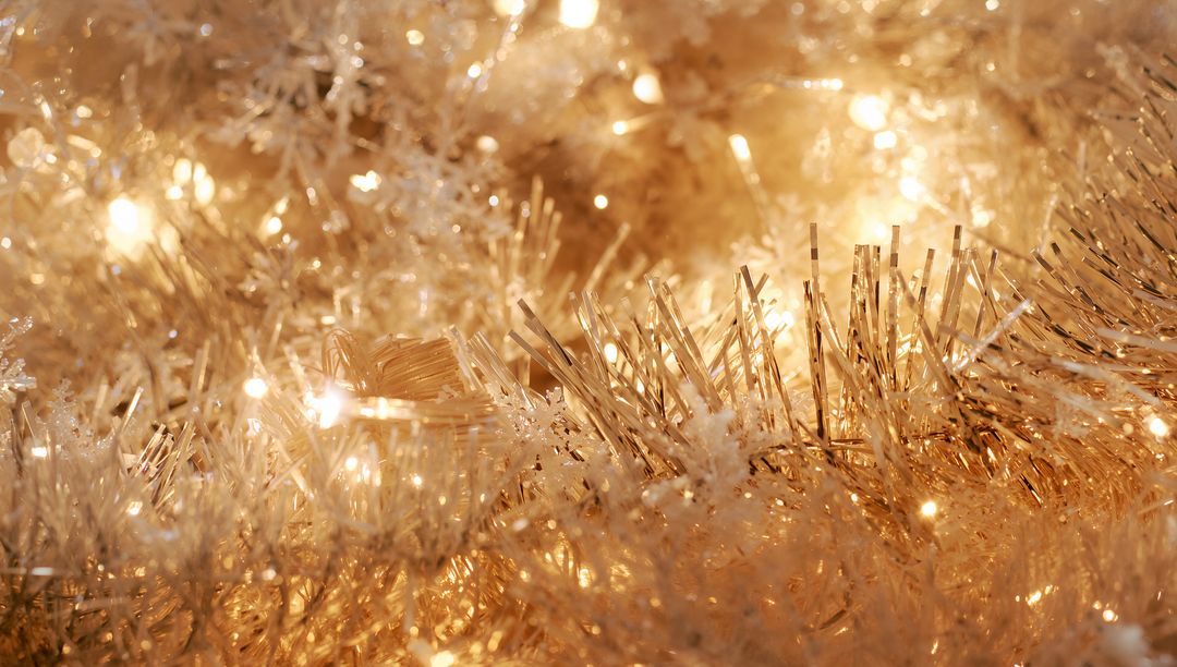 Golden tinsel and warm LED lights creating glittering bokeh holiday sparkle closeup