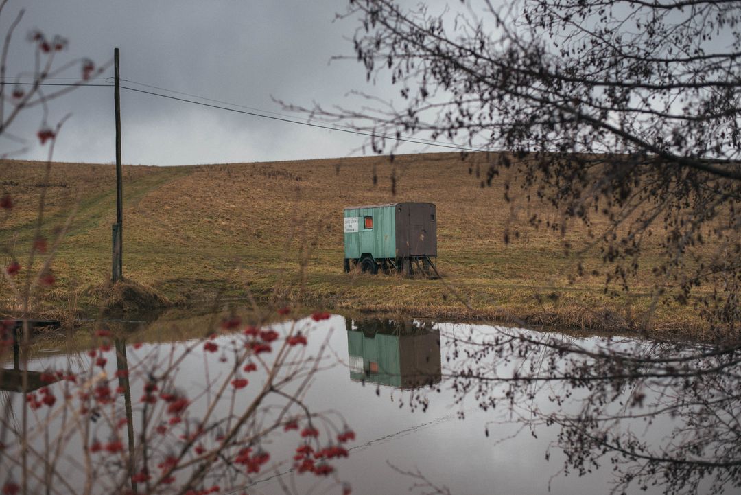 Lonely Countryside Shack by Reflective Pond on Overcast Day - Free Images, Stock Photos and Pictures on Pikwizard.com