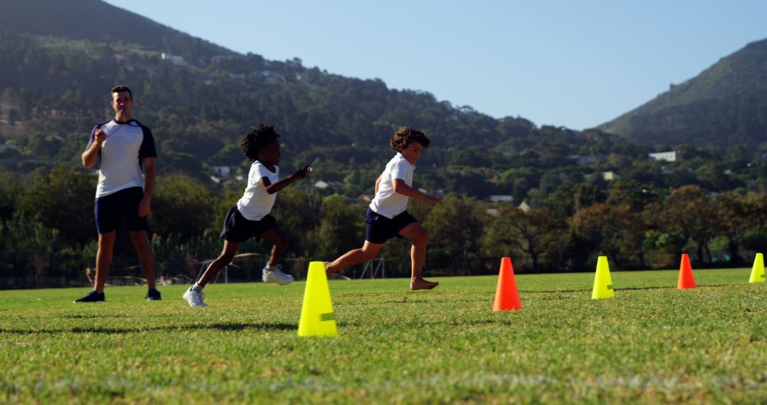 Children Running Through Cones with Coach on Sunny Day - Free Images, Stock Photos and Pictures on Pikwizard.com