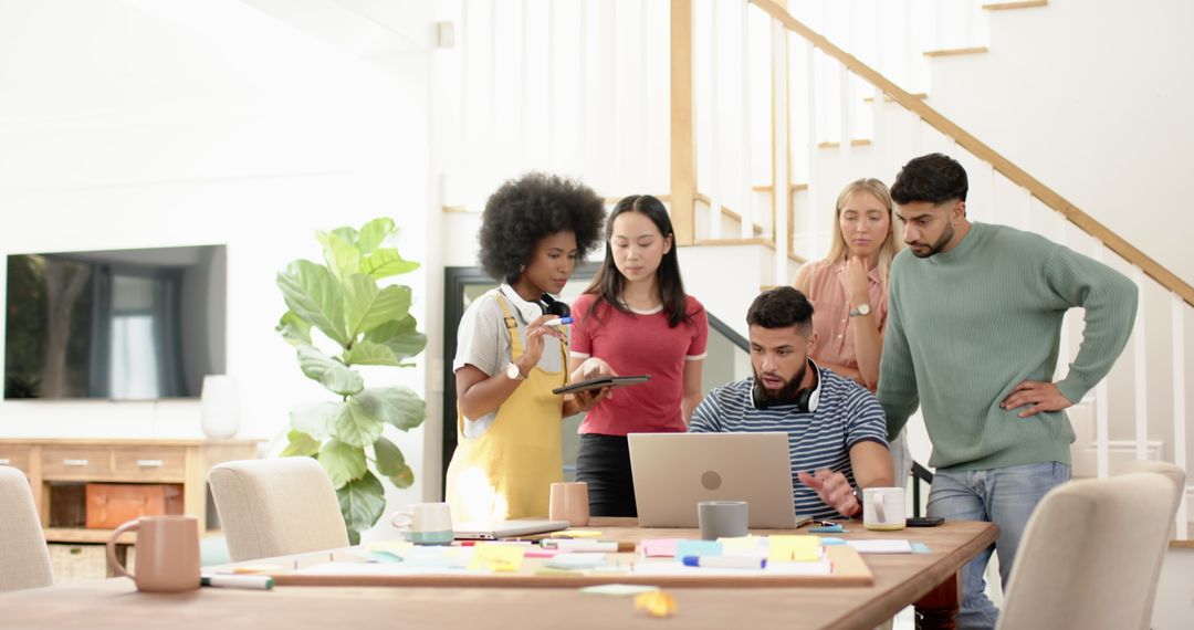 Diverse Team Collaborates With Laptop and Tablet at Home Workspace