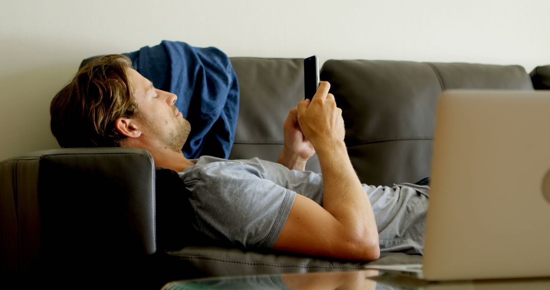 Relaxed Young Man Lounging on Couch Using Smartphone - Free Images, Stock Photos and Pictures on Pikwizard.com