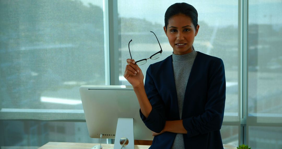 Confident Businesswoman Holding Glasses in Office Environment - Free Images, Stock Photos and Pictures on Pikwizard.com