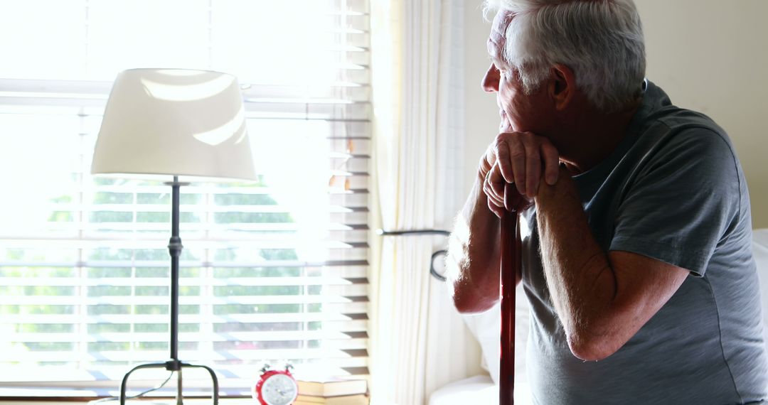 Senior Man Reflecting by Window with a Cane - Free Images, Stock Photos and Pictures on Pikwizard.com