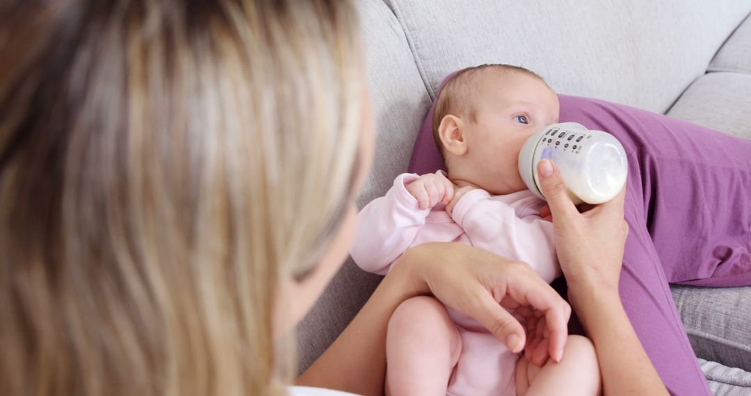 Mother Feeding Infant with Bottle on Sofa - Free Images, Stock Photos and Pictures on Pikwizard.com