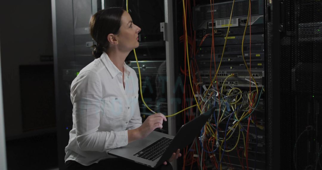 IT Technician Tracing Ethernet Cable in Server Room with Laptop