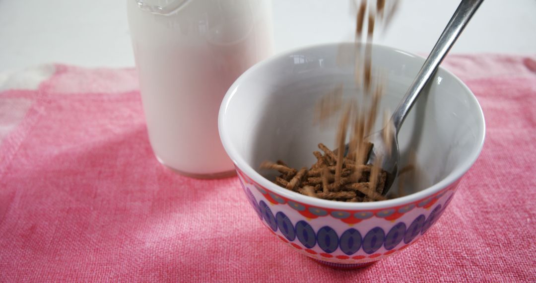 Pouring Cereal into Decorative Bowl with Milk on Pink Cloth - Free Images, Stock Photos and Pictures on Pikwizard.com