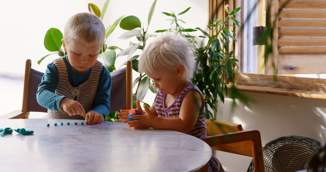 Two Young Children Creatively Engaging with Clay Around Table