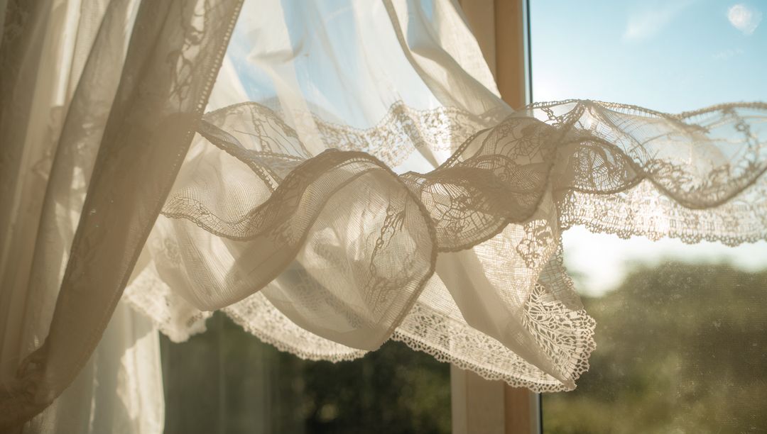 Sunlit Sheer Lace Curtain Billowing at Window with Scalloped Trim and Warm Backlight