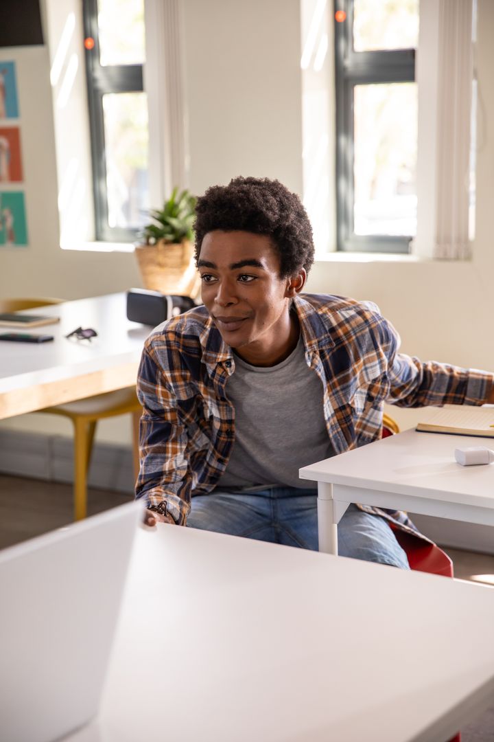Young Man Engaged in Study at Bright Workspace with Laptop