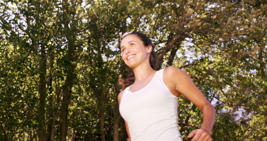 Young Woman Jogging Outdoors in Green Forest on Sunny Day - Free Images, Stock Photos and Pictures on Pikwizard.com