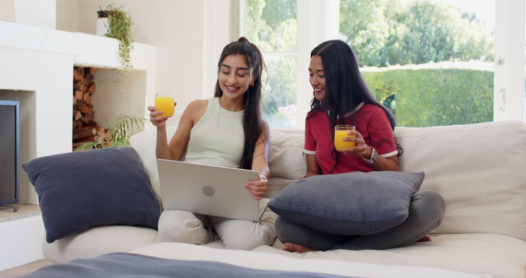 Two Friends Relaxing at Home with Juice and Laptop