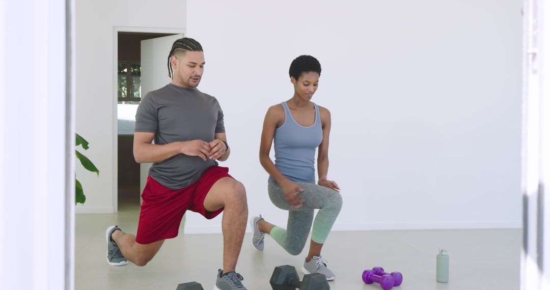 Diverse Athletes Lunging With Dumbbells in Home Gym