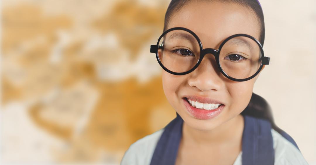 Young Girl Smiling with Large Glasses in Front of Blurry Brown Map - Free Images, Stock Photos and Pictures on Pikwizard.com
