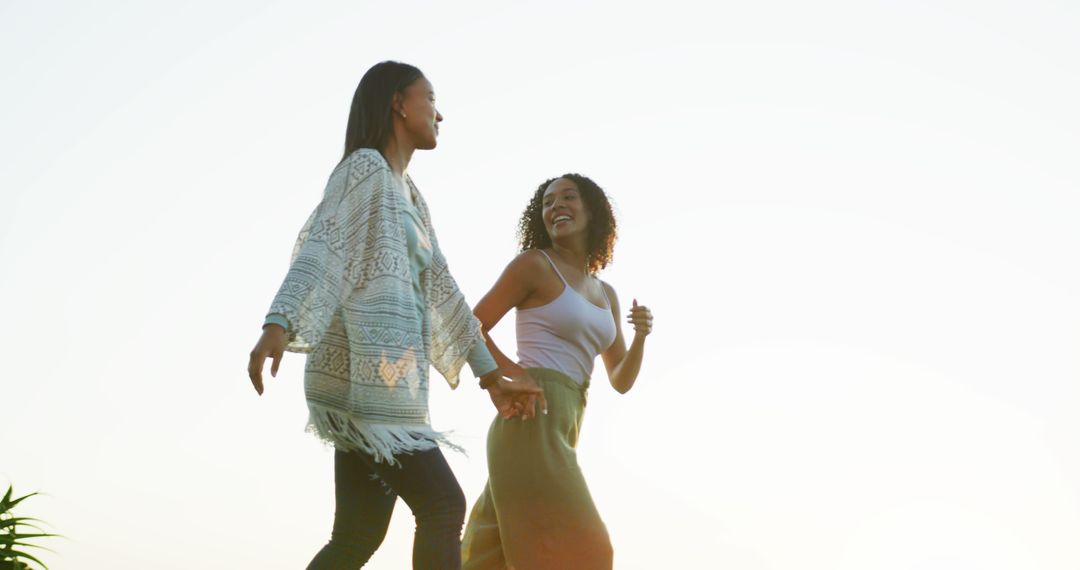 Two African American Women Walking Outdoors Holding Hands at Sunset - Free Images, Stock Photos and Pictures on Pikwizard.com