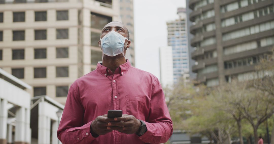 Man Wearing Face Mask Using Smartphone Outdoors in Urban Area - Free Images, Stock Photos and Pictures on Pikwizard.com