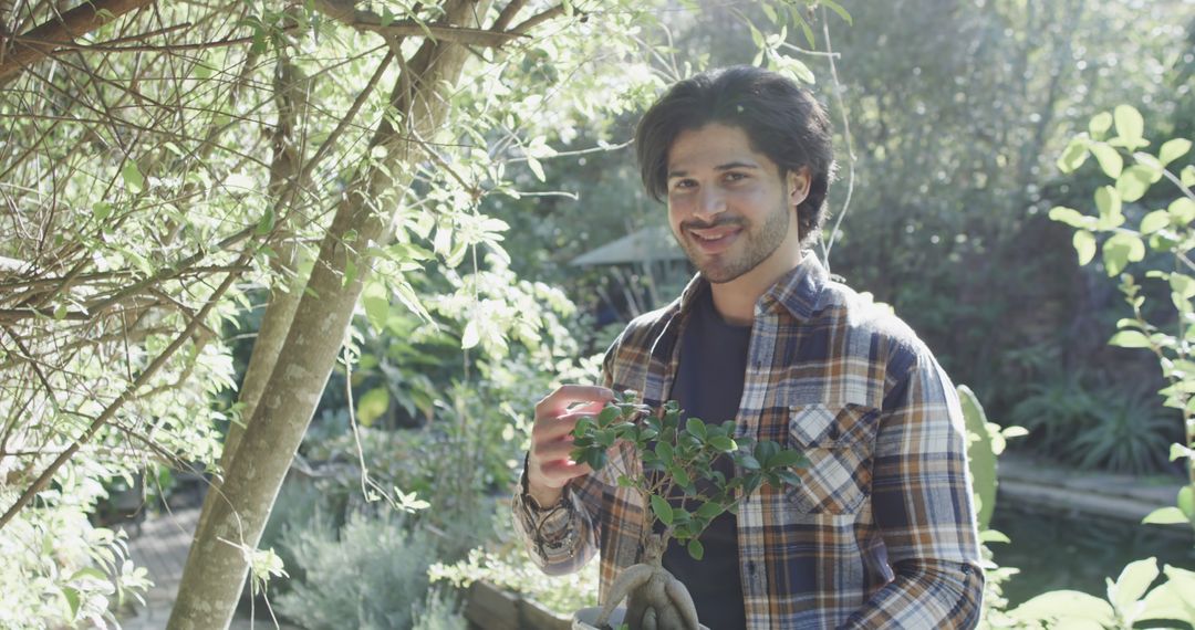 Young Man Tending Plants During Sunny Day in Lush Garden - Free Images, Stock Photos and Pictures on Pikwizard.com