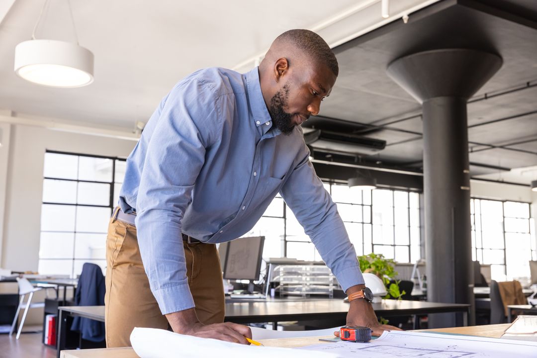 Architect Reviewing Blueprints in Modern Office Workspace