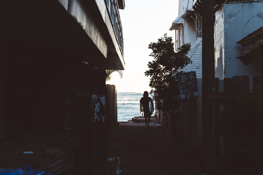 Person Walking Towards Ocean During Sunset in Narrow Alley - Free Images, Stock Photos and Pictures on Pikwizard.com