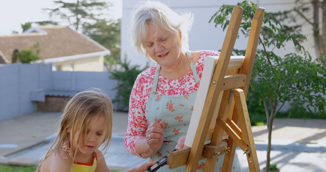 Grandmother and Granddaughter Painting Together Outdoors on Sunny Day - Free Images, Stock Photos and Pictures on Pikwizard.com