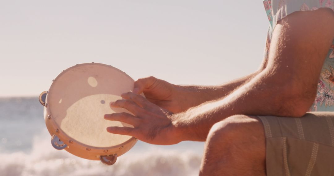 Man Playing Tambourine on Beach at Sunset - Free Images, Stock Photos and Pictures on Pikwizard.com