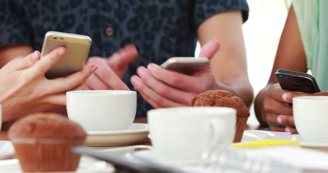 Friends Using Smartphones at Cafe Table with Muffins and Coffee Cups - Free Images, Stock Photos and Pictures on Pikwizard.com