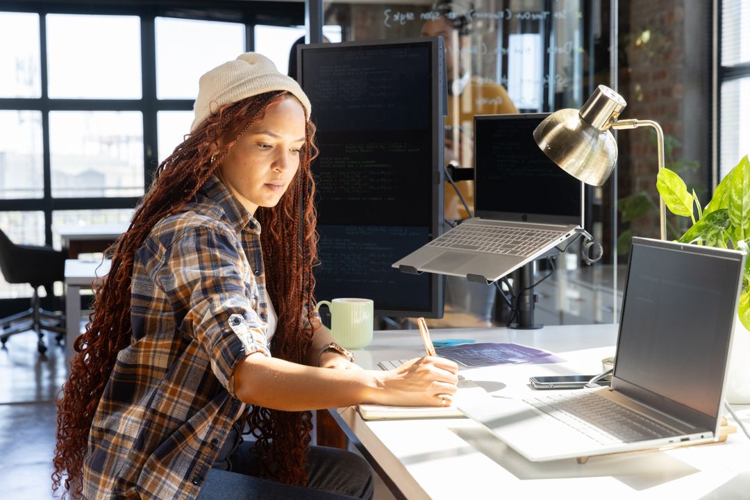 Young Programmer Taking Notes while Working on Project in Urban Office