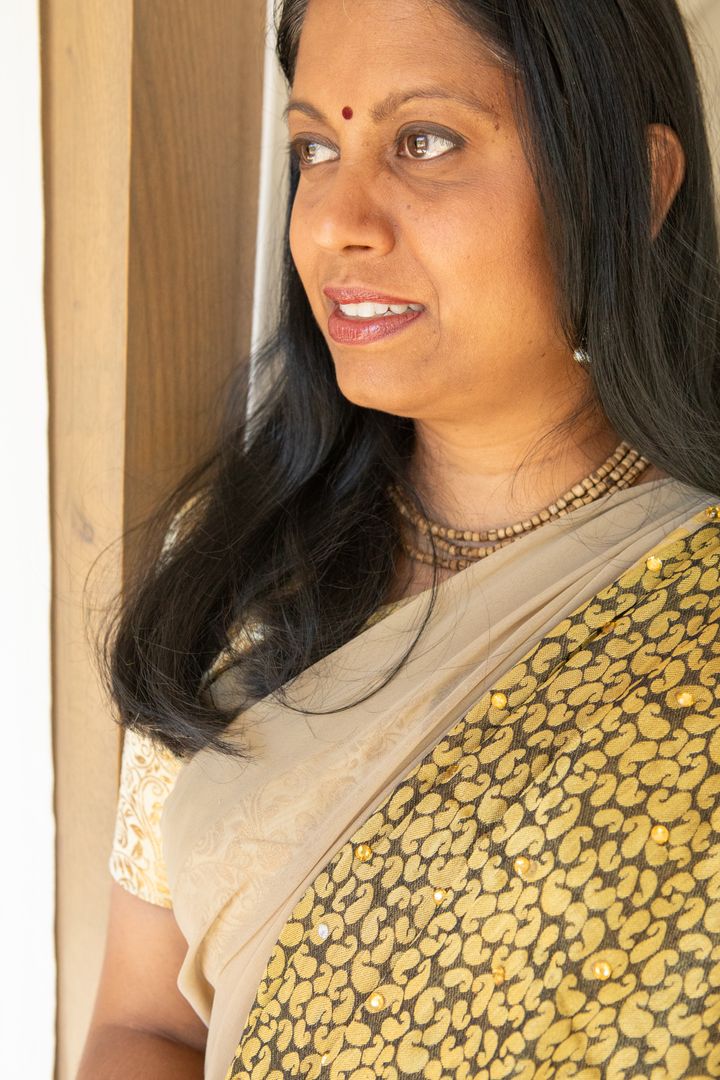 Elegant Indian Woman in Gold Embellished Sari Near Window