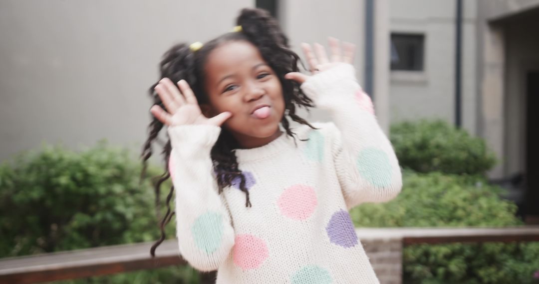 Playful Girl making Silly Face in Courtyard by Greenery