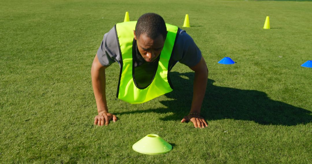 Athlete Training on Field with Push-Up Exercise and Cones - Free Images, Stock Photos and Pictures on Pikwizard.com