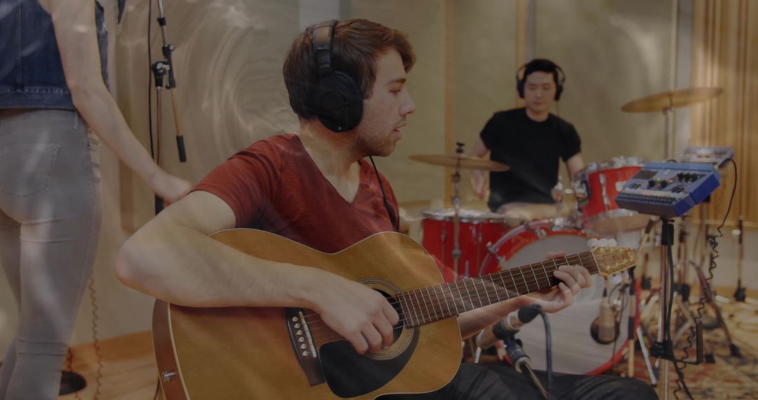 Musicians recording in studio with acoustic guitar and drums