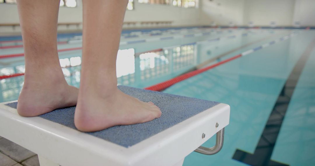 Focused Swimmer Poised on Diving Block at Pristine Lap Pool